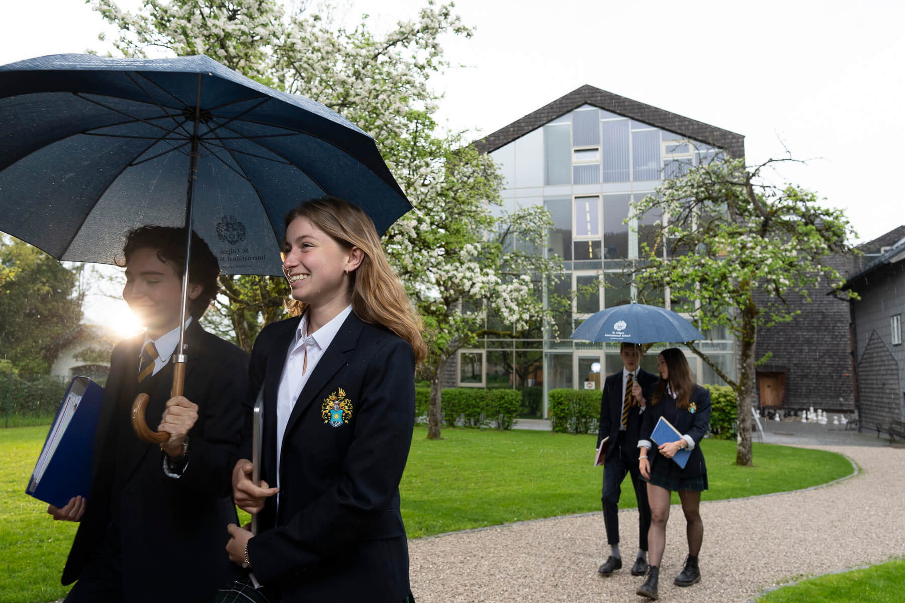 Students walking outside St. Gilgen International Boarding School on a rainy spring day
